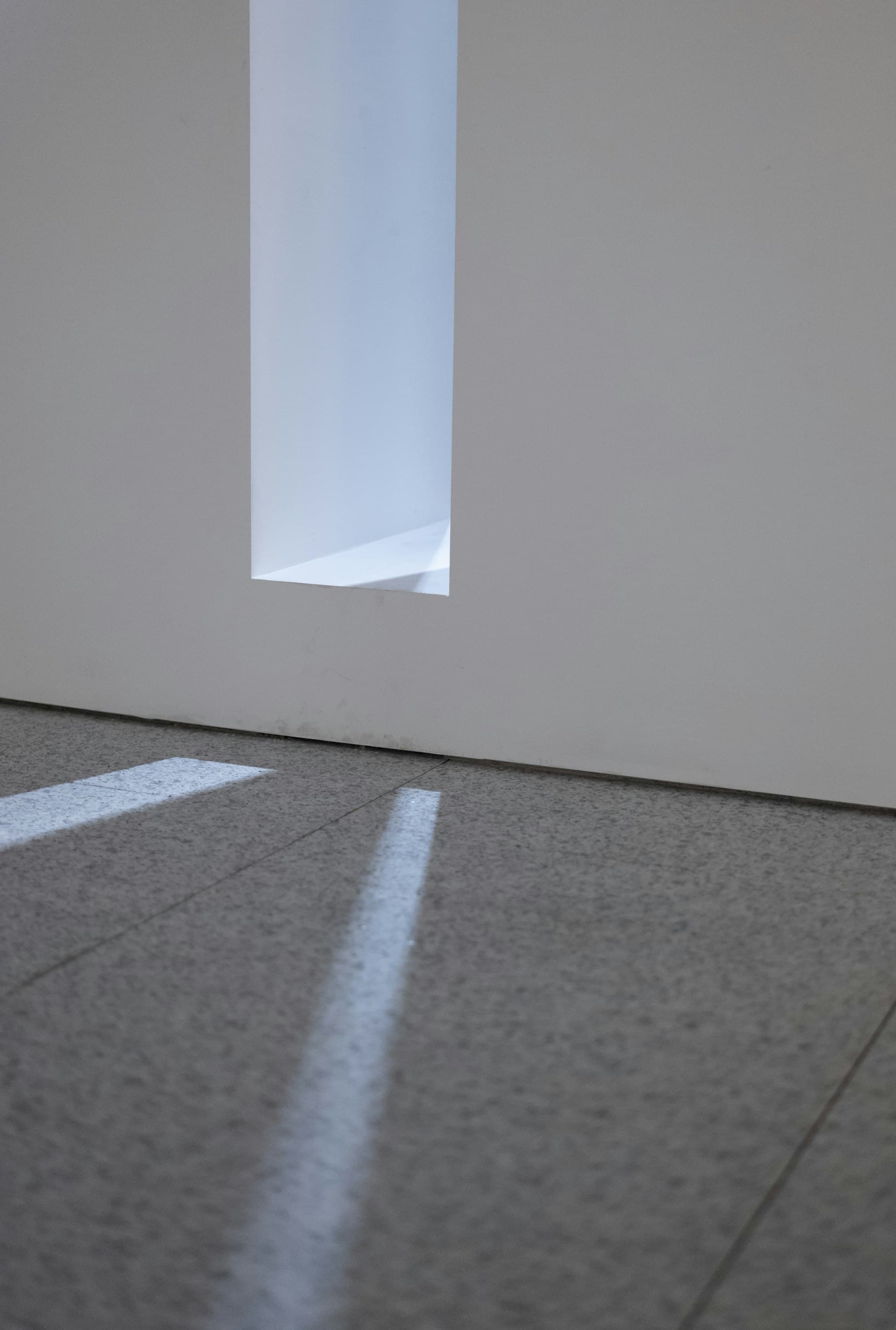 A quiet empty room with a shaft of daylight falling through a window across the floor.