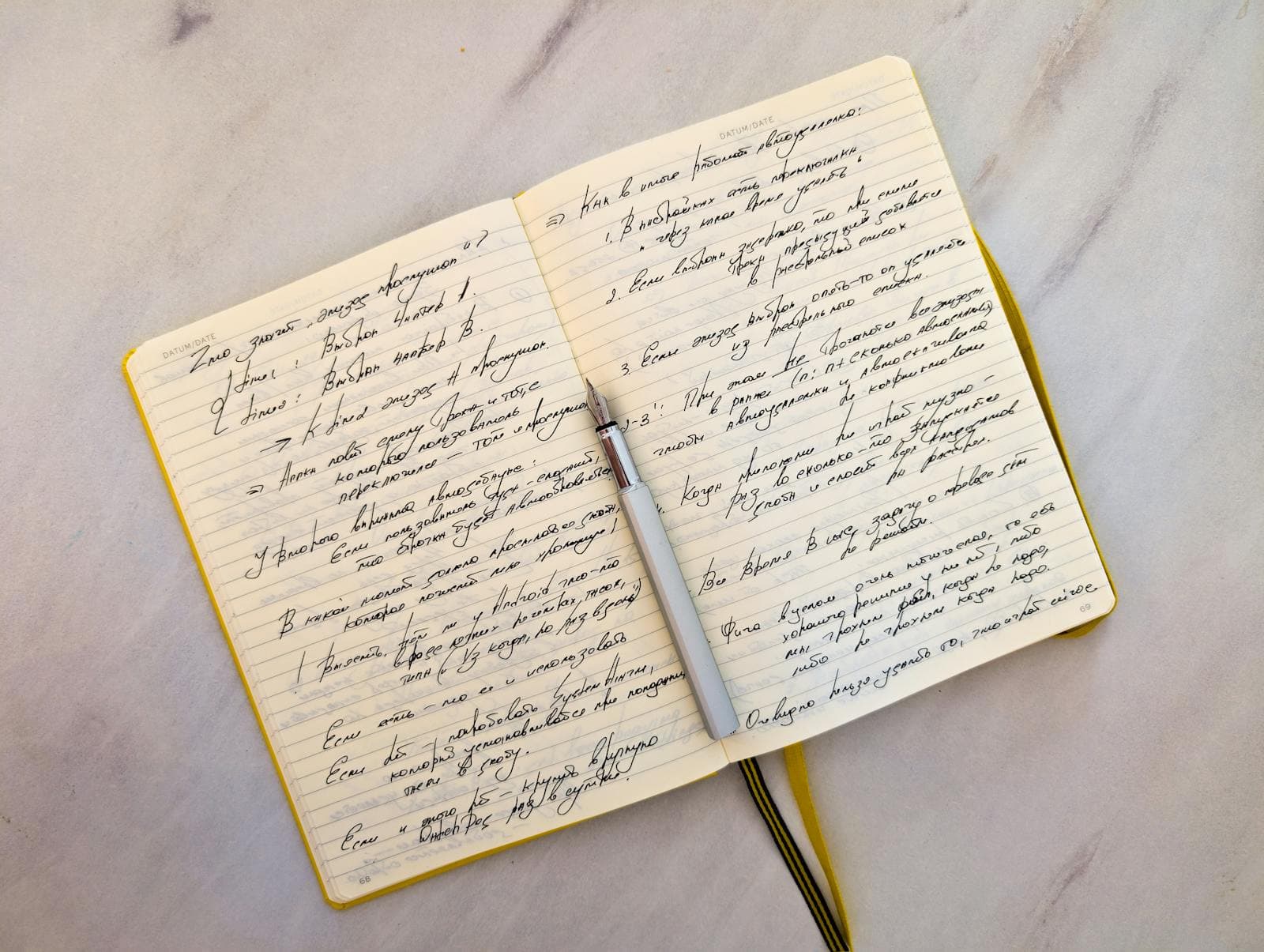 An open notebook with handwritten cursive notes and a pen resting across the page.